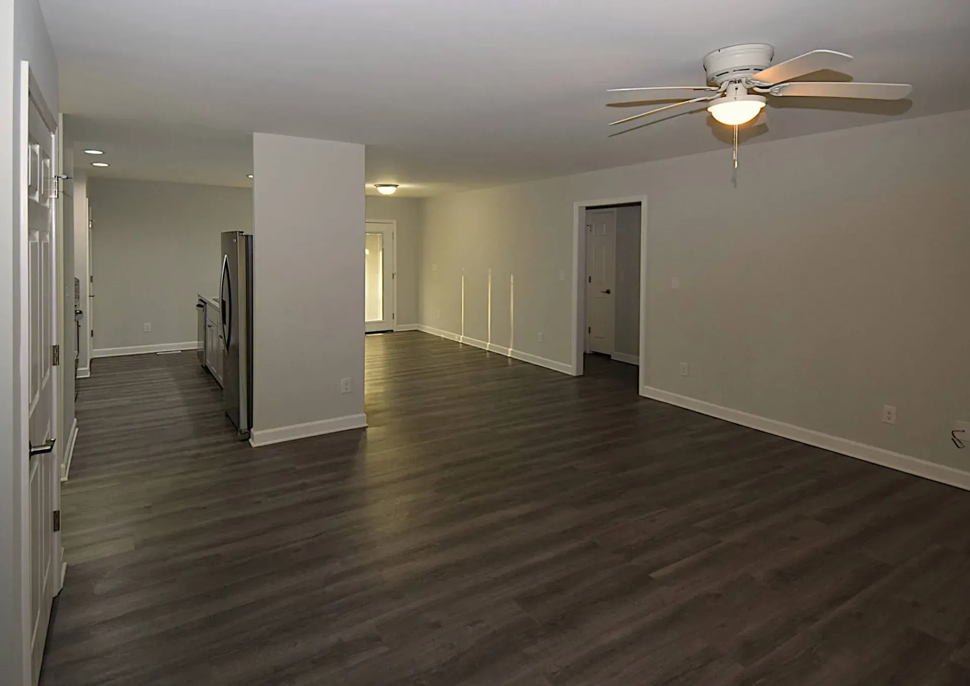 An empty living room with hardwood floors and a ceiling fan.
