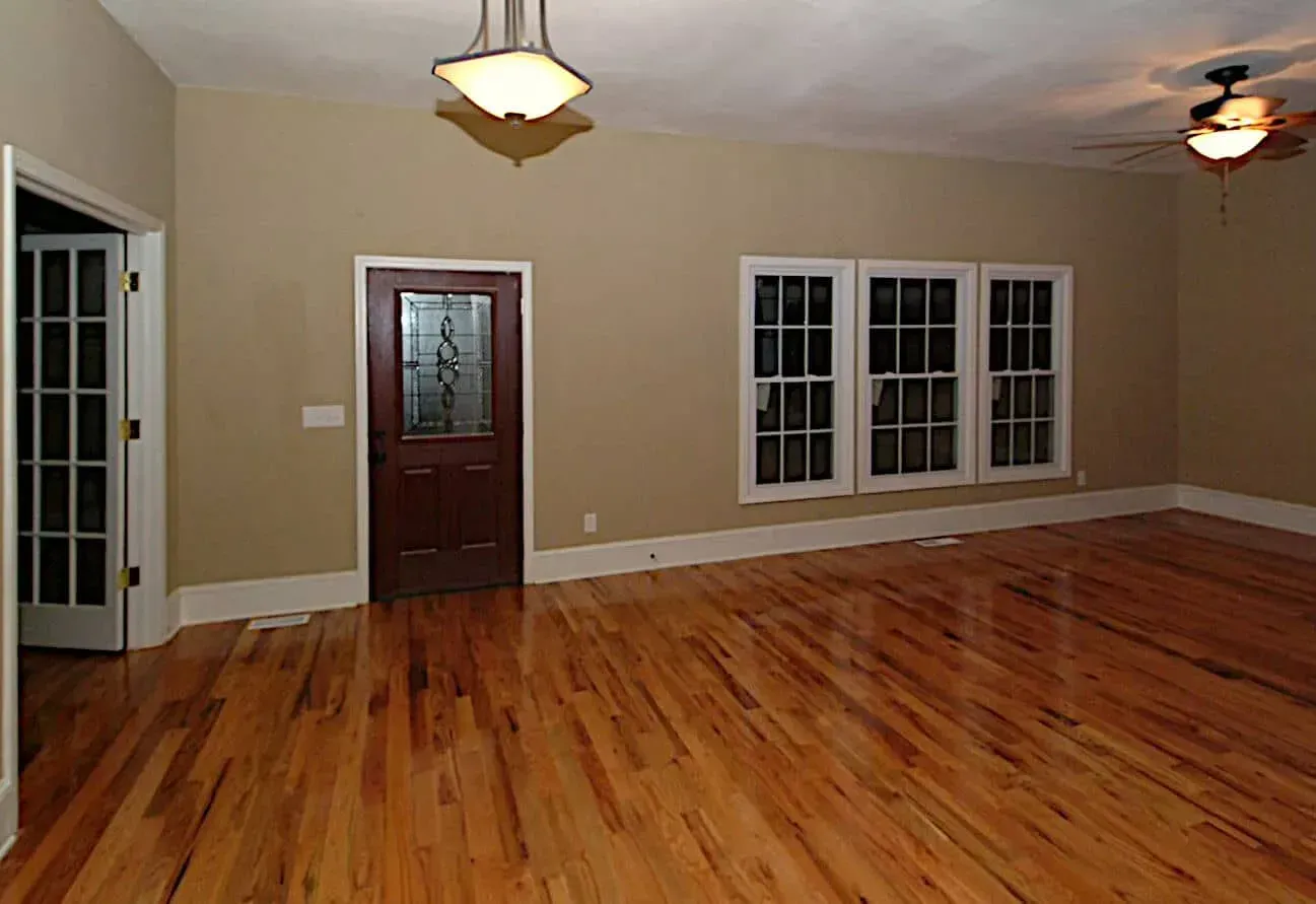 An empty living room with hardwood floors and a ceiling fan.