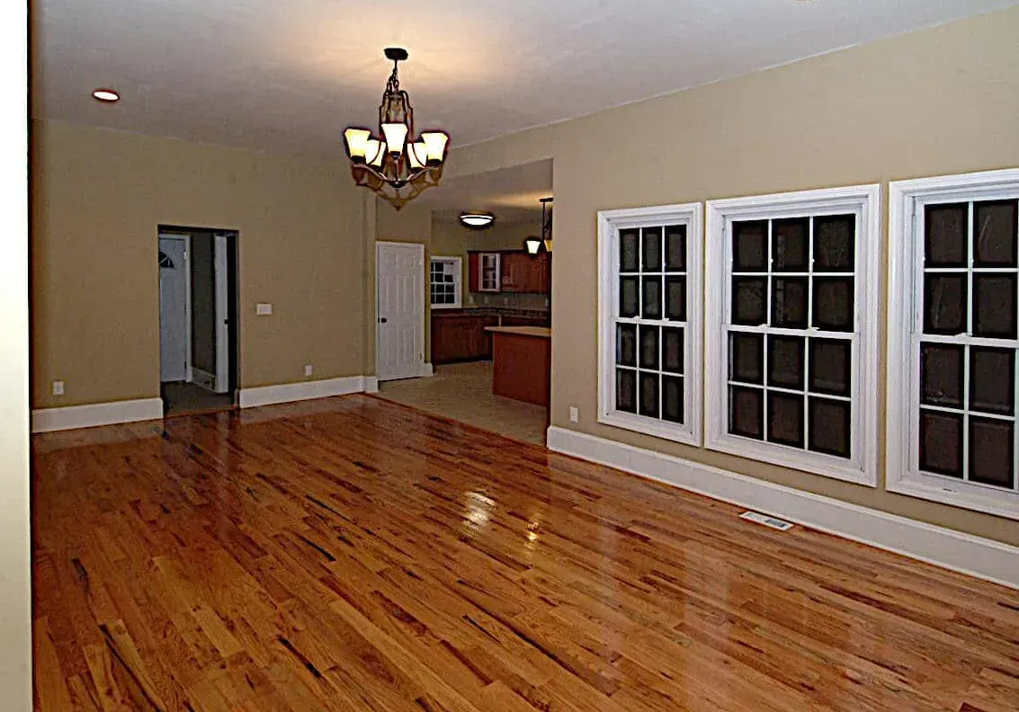 An empty living room with hardwood floors and a chandelier.