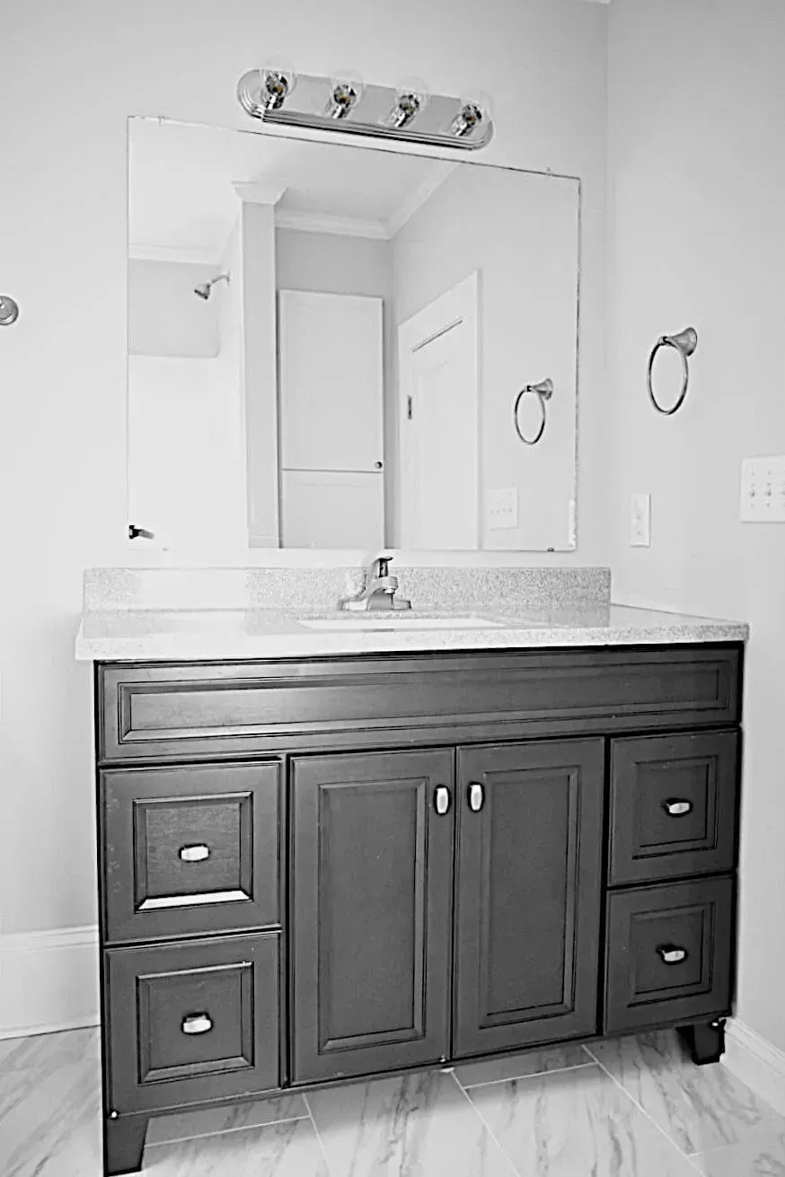 A black and white photo of a bathroom vanity with a sink and mirror.
