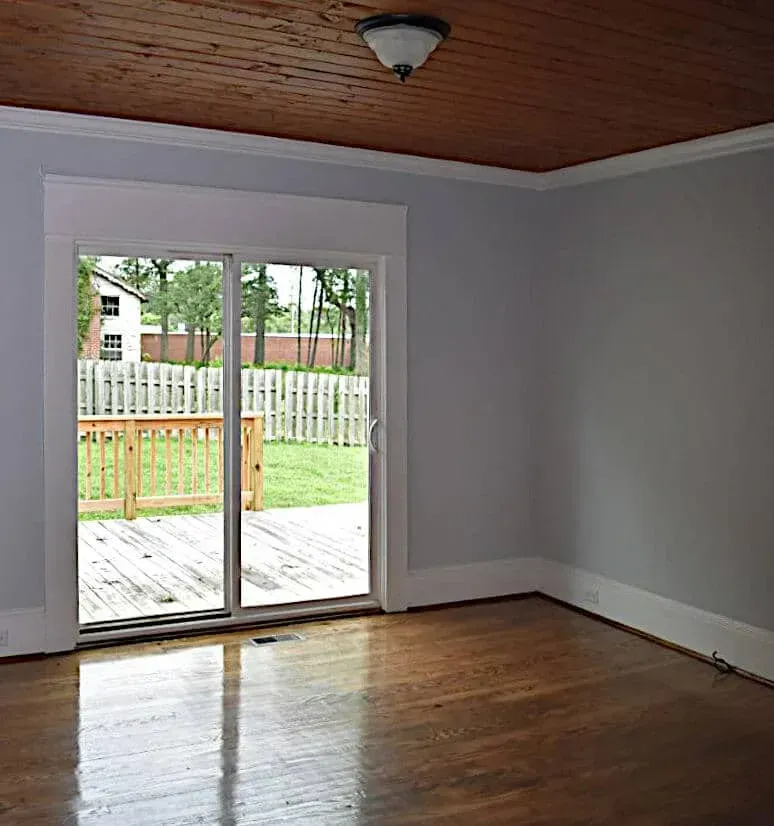 An empty room with a sliding glass door leading to a deck