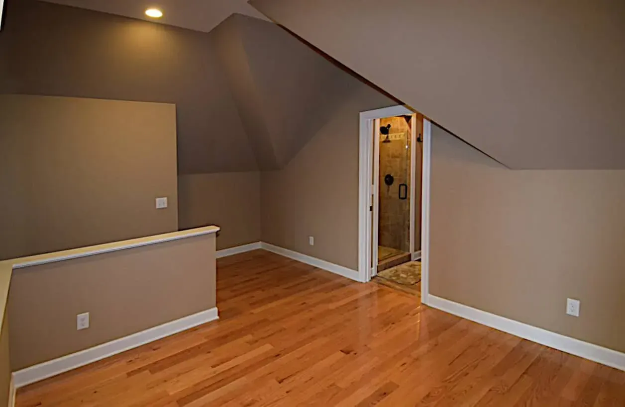 An empty room with hardwood floors and a staircase leading to a bathroom.