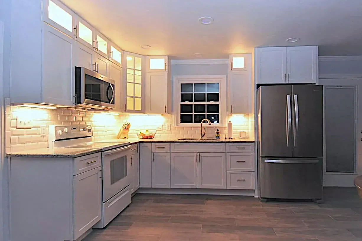 A kitchen with white cabinets , stainless steel appliances , a refrigerator and a microwave.
