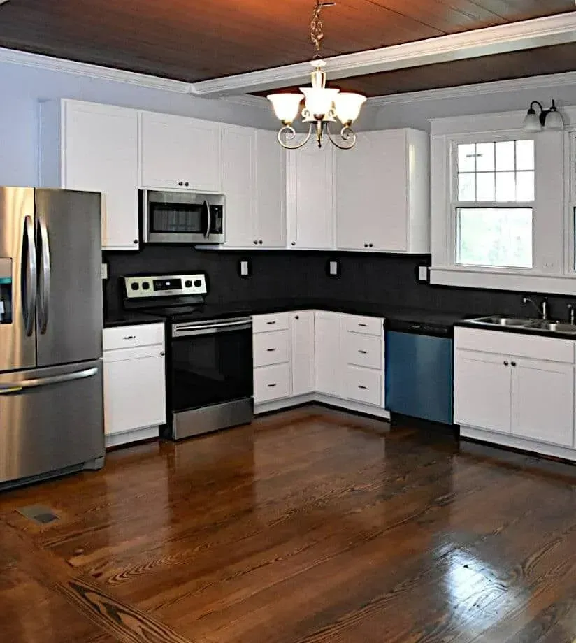 A kitchen with stainless steel appliances , white cabinets , hardwood floors and a stainless steel refrigerator.