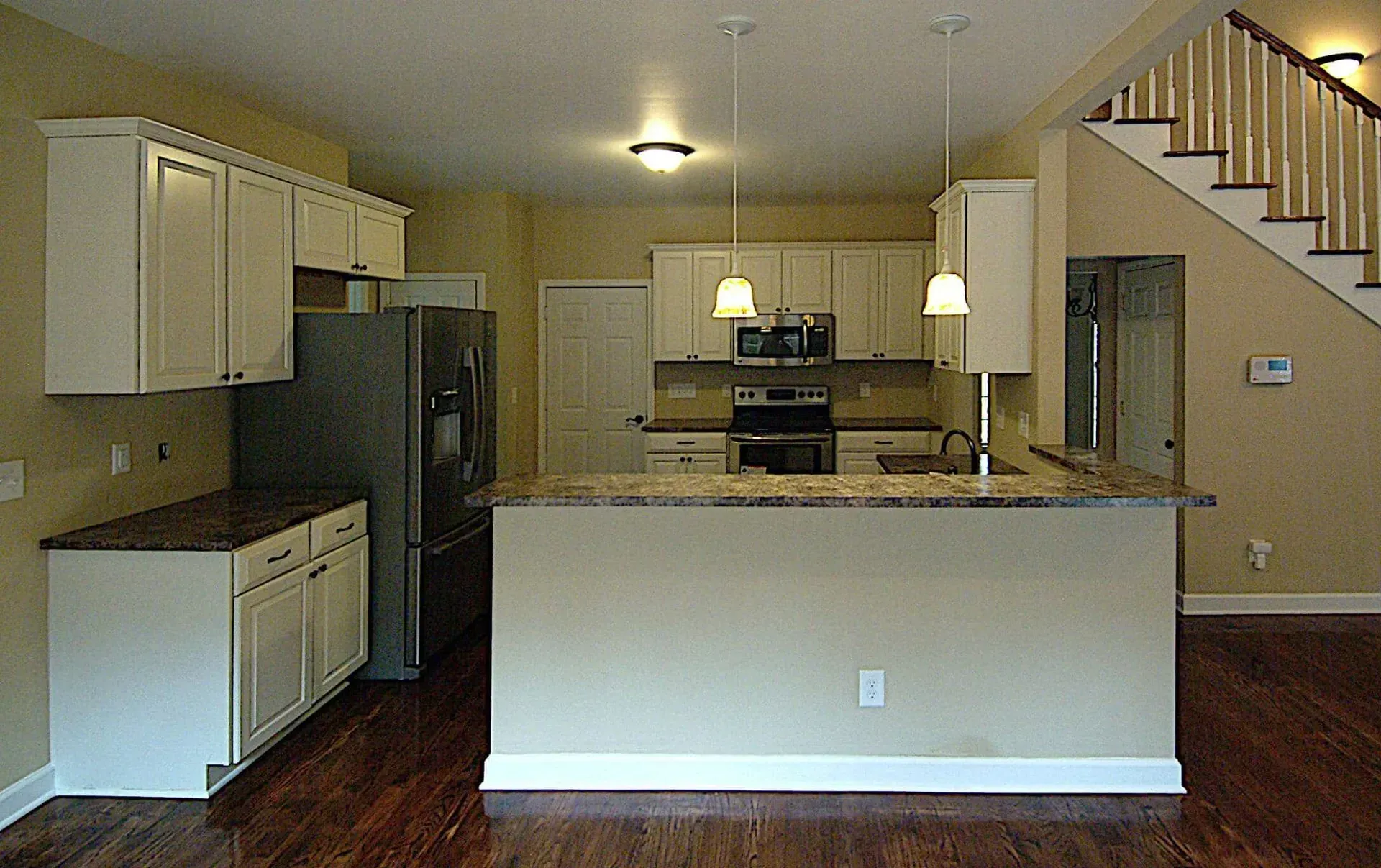 An empty kitchen with a staircase in the background