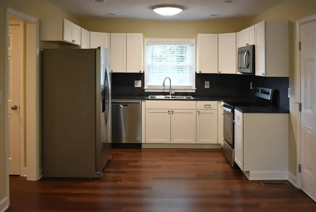 An empty kitchen with white cabinets and stainless steel appliances