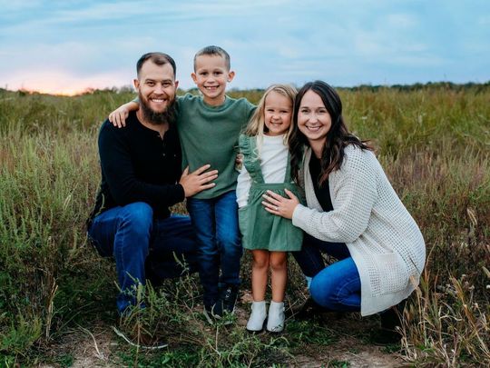 A family is posing for a picture with two children.