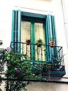 A balcony with green shutters and potted plants on it