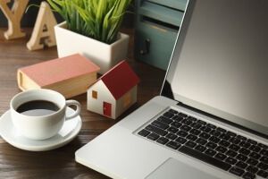 A cup of coffee is sitting next to a laptop on a wooden table.