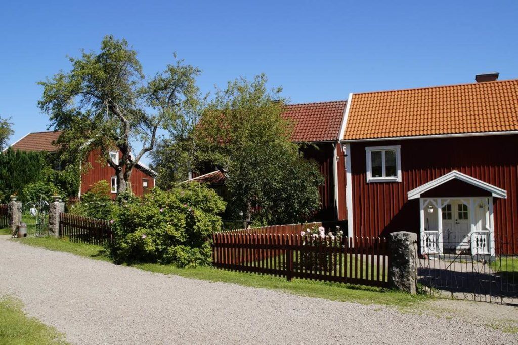 A red house with a white trim sits on a gravel road