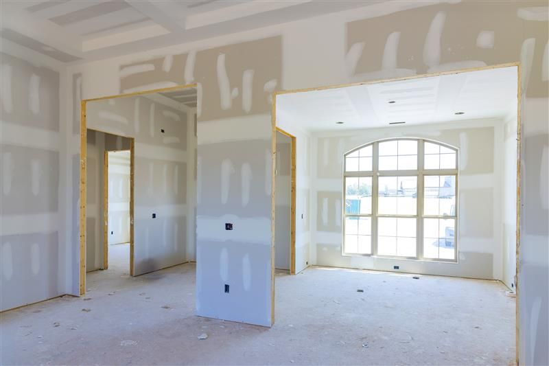 Interior room under construction with drywall, unfinished walls, and a large window.
