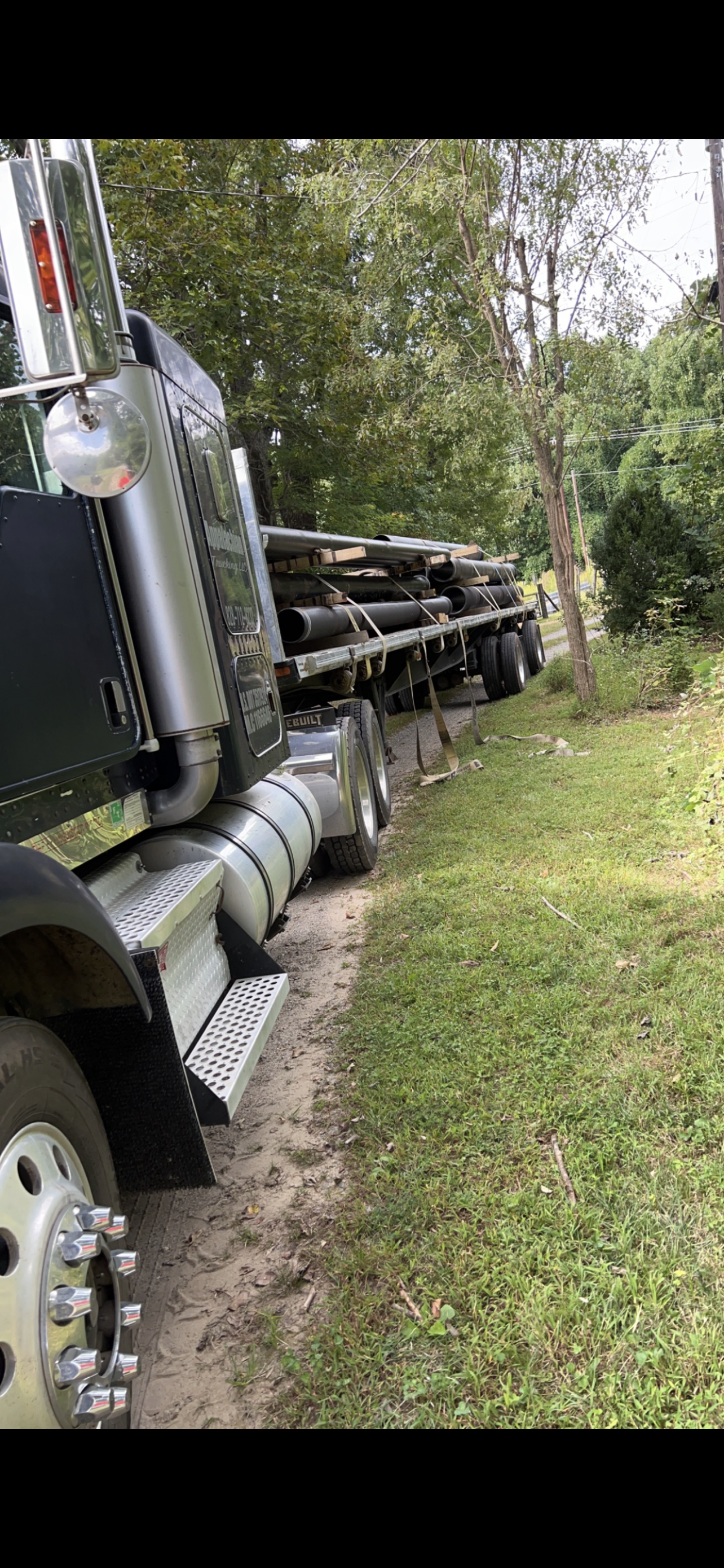 A Semi Truck is Driving Down a Dirt Road Next to a Grassy Field | Weaverville, NC | Appalachian Trucking LLC