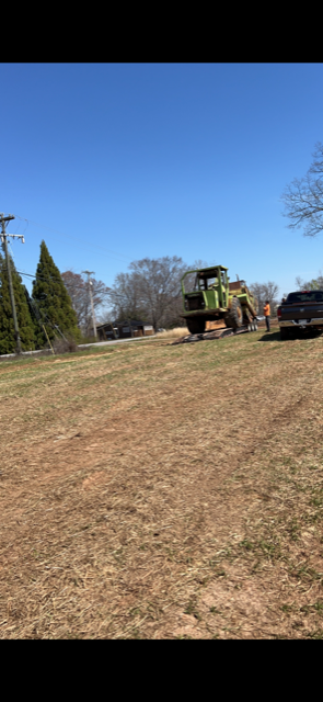 Green Tractor is Driving Down a Dirt Road in a Field | Weaverville, NC | Appalachian Trucking LLC