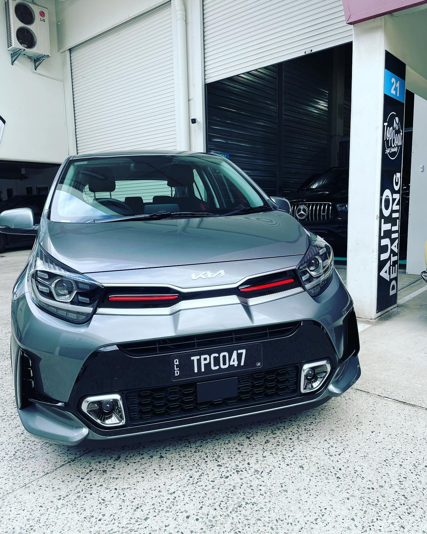 A gray car is parked in front of a building.