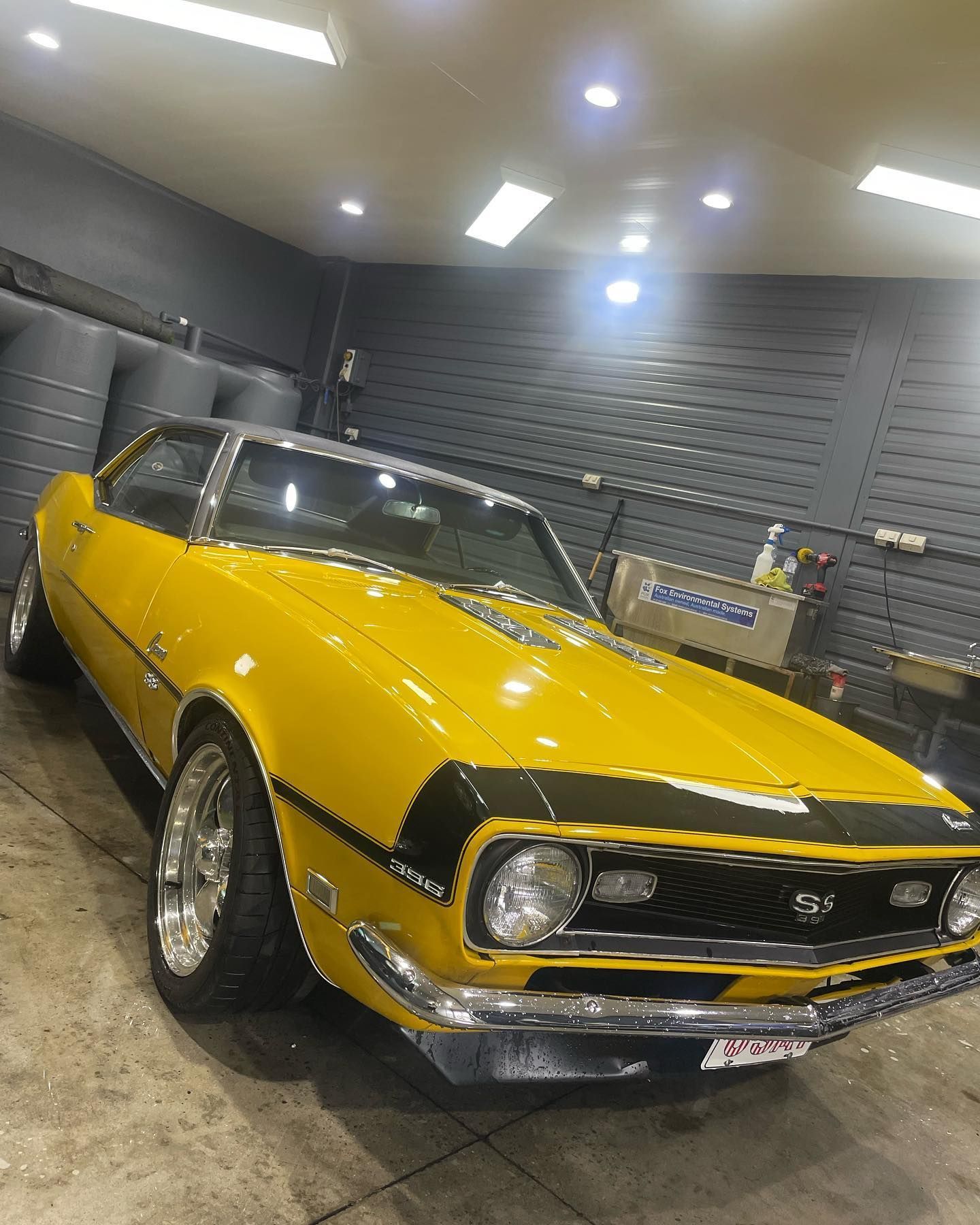 A yellow chevrolet camaro is parked in a garage.