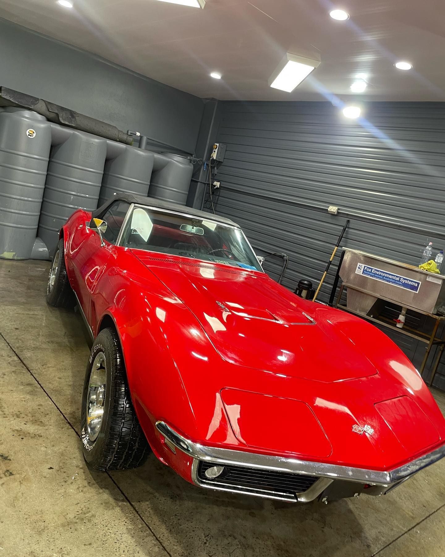 A red corvette convertible is parked in a garage.