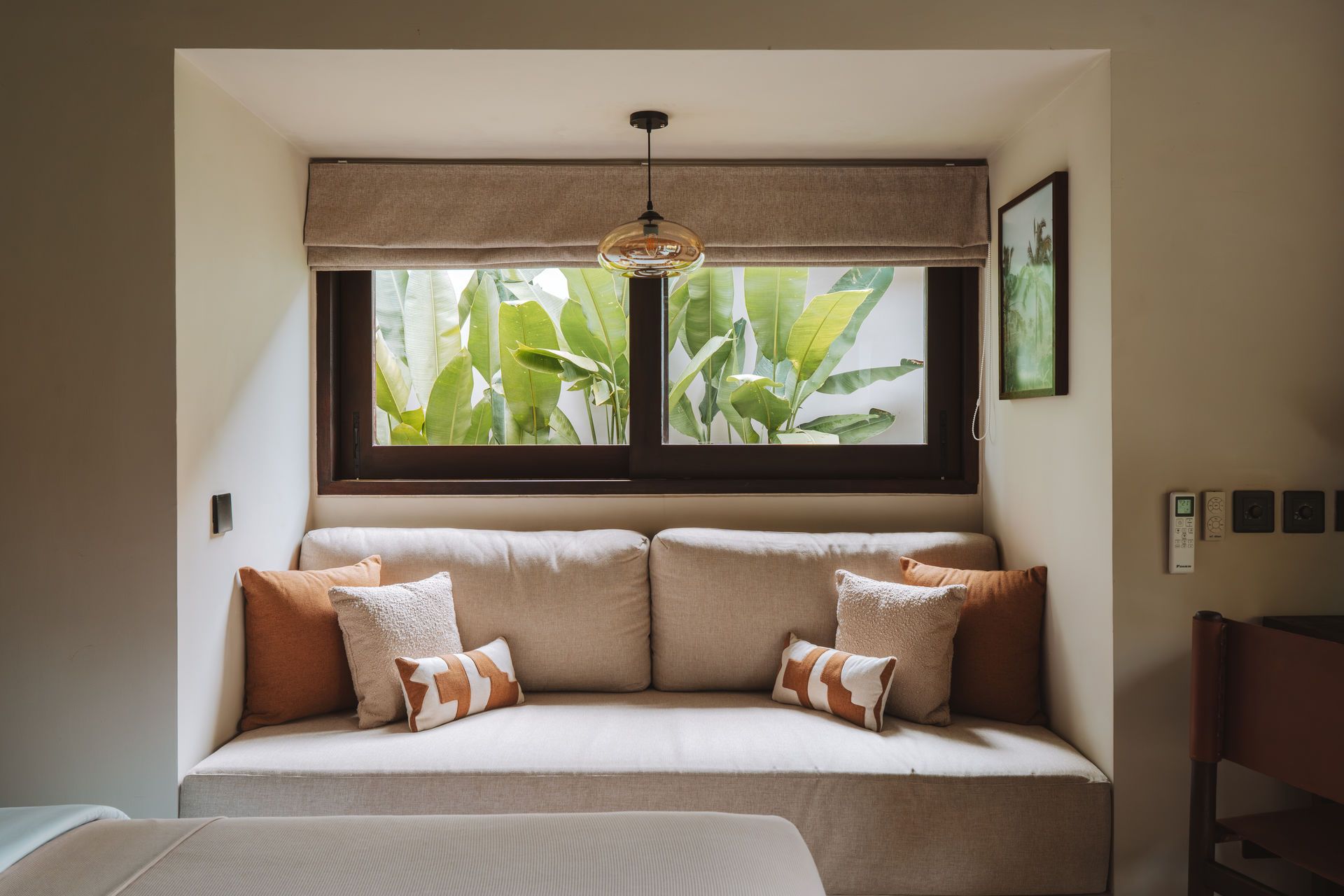 Cozy window seat with beige cushions, patterned pillows, and greenery visible outside