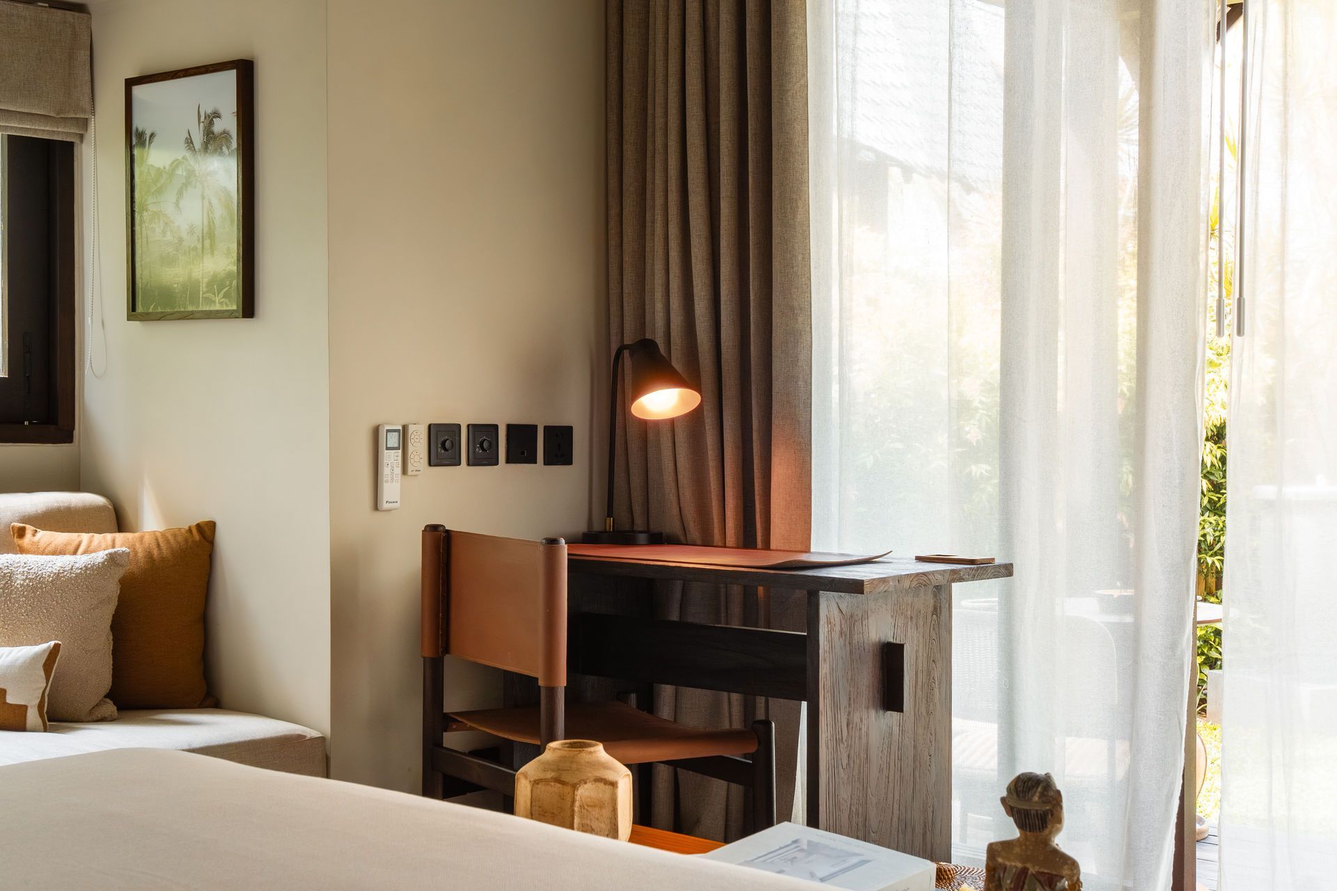 Cozy bedroom with bed, desk, lamp, and curtains beside a bright window