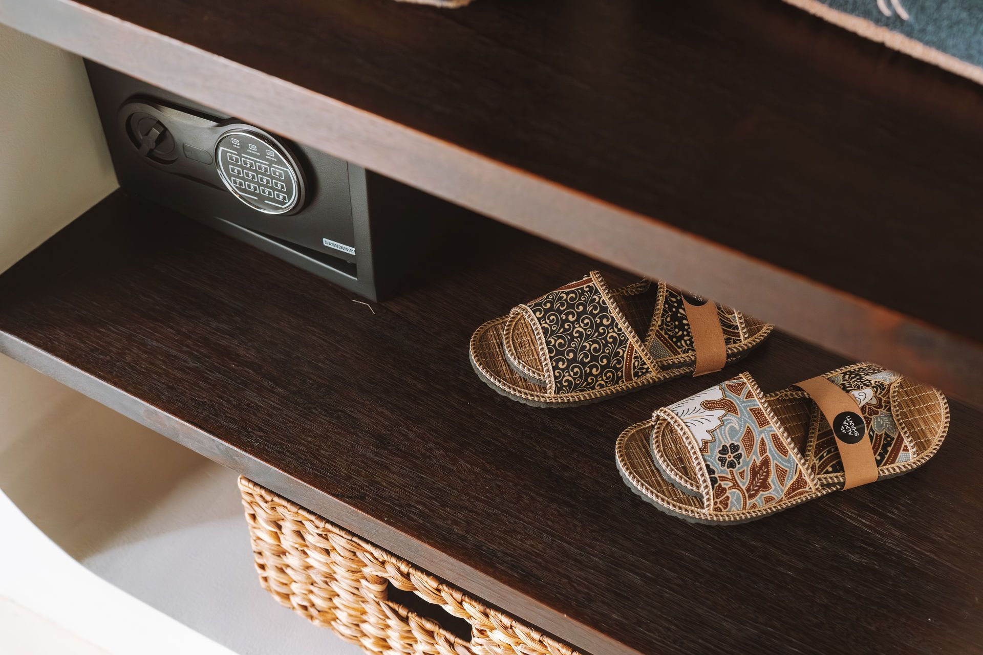 Dark wood shelf with leopard-print sandals, a wall safe, and a woven basket underneath