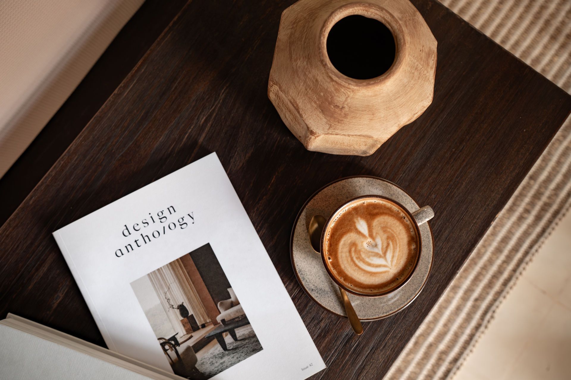 Coffee cup, vase, and a book on a dark wooden tray with soft natural light