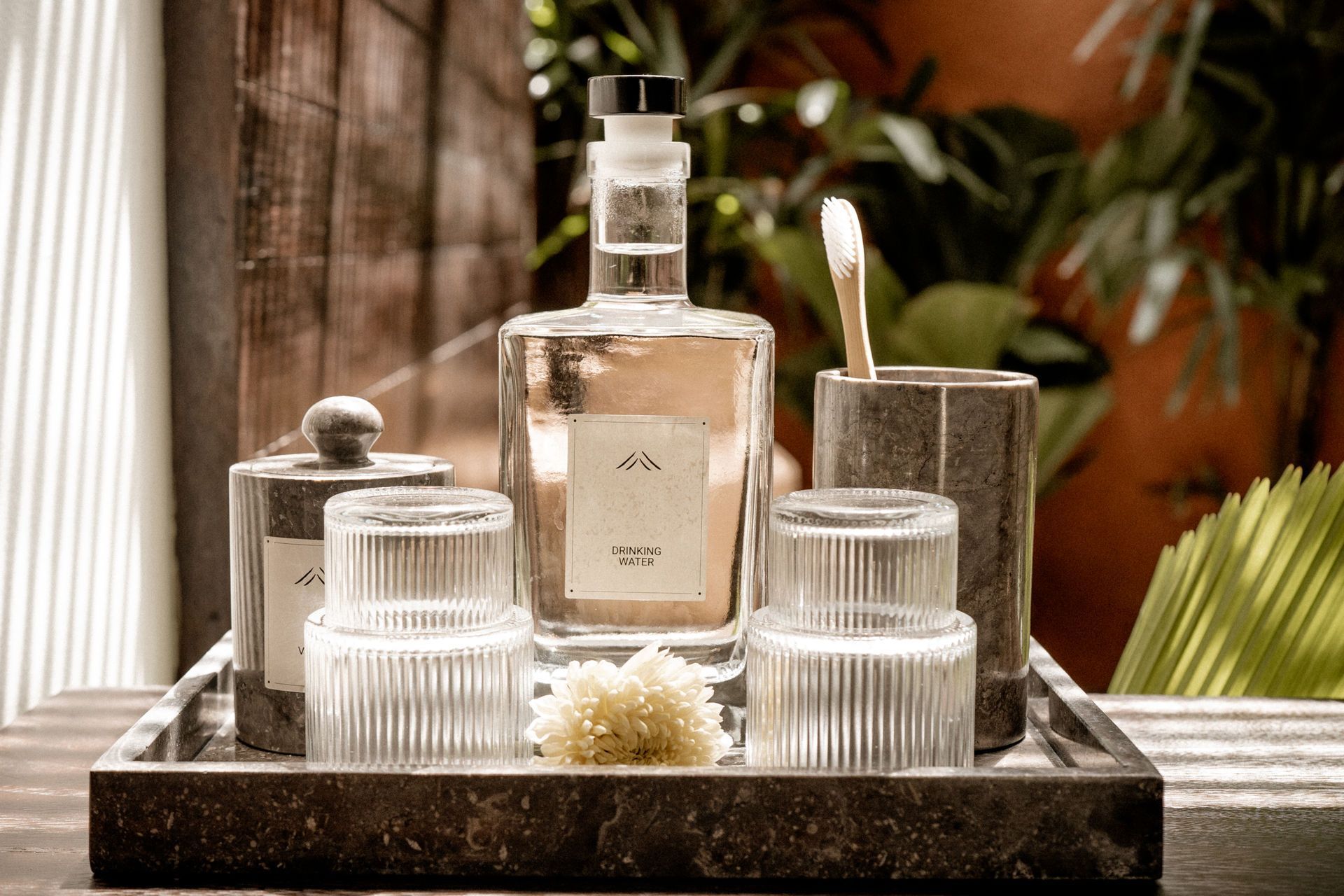 Perfume bottle and scented candles on a tray with a reed diffuser in a spa-like setting