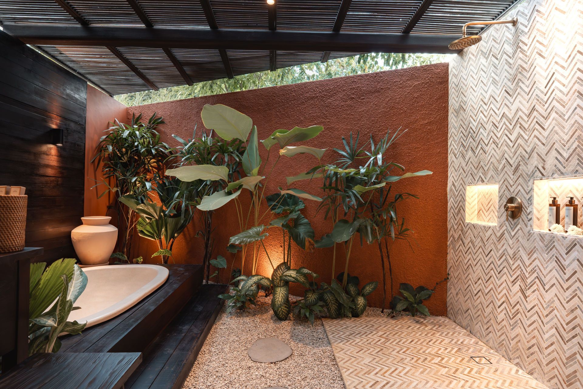 Indoor spa shower area with plants, pebble floor, and textured walls in warm lighting