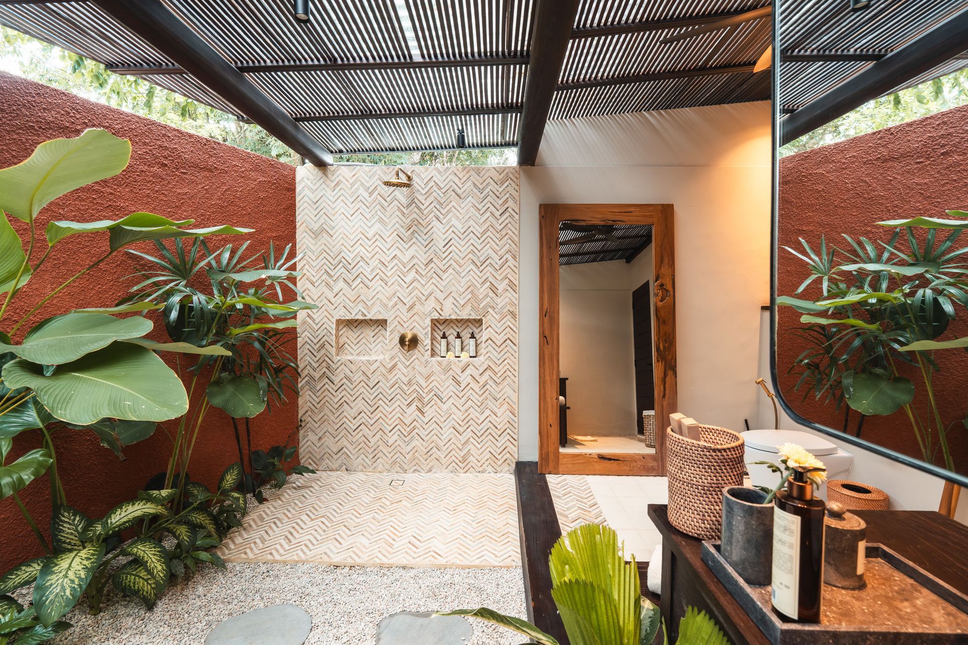 Open-air patio with woven wall, mirror, plants, and a shaded corrugated roof