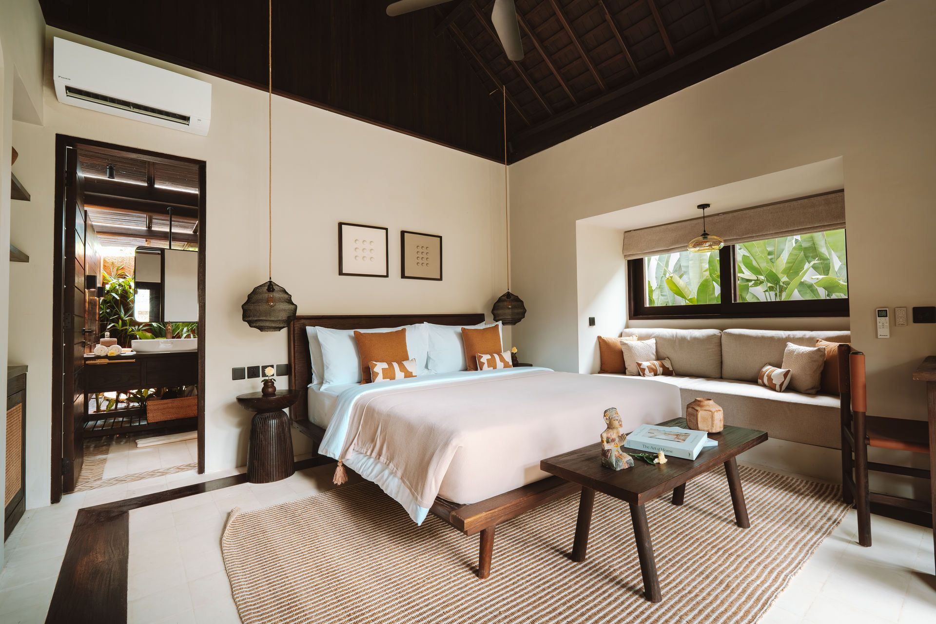 Modern bedroom with king bed, woven rug, wooden ceiling, and window seat by large windows