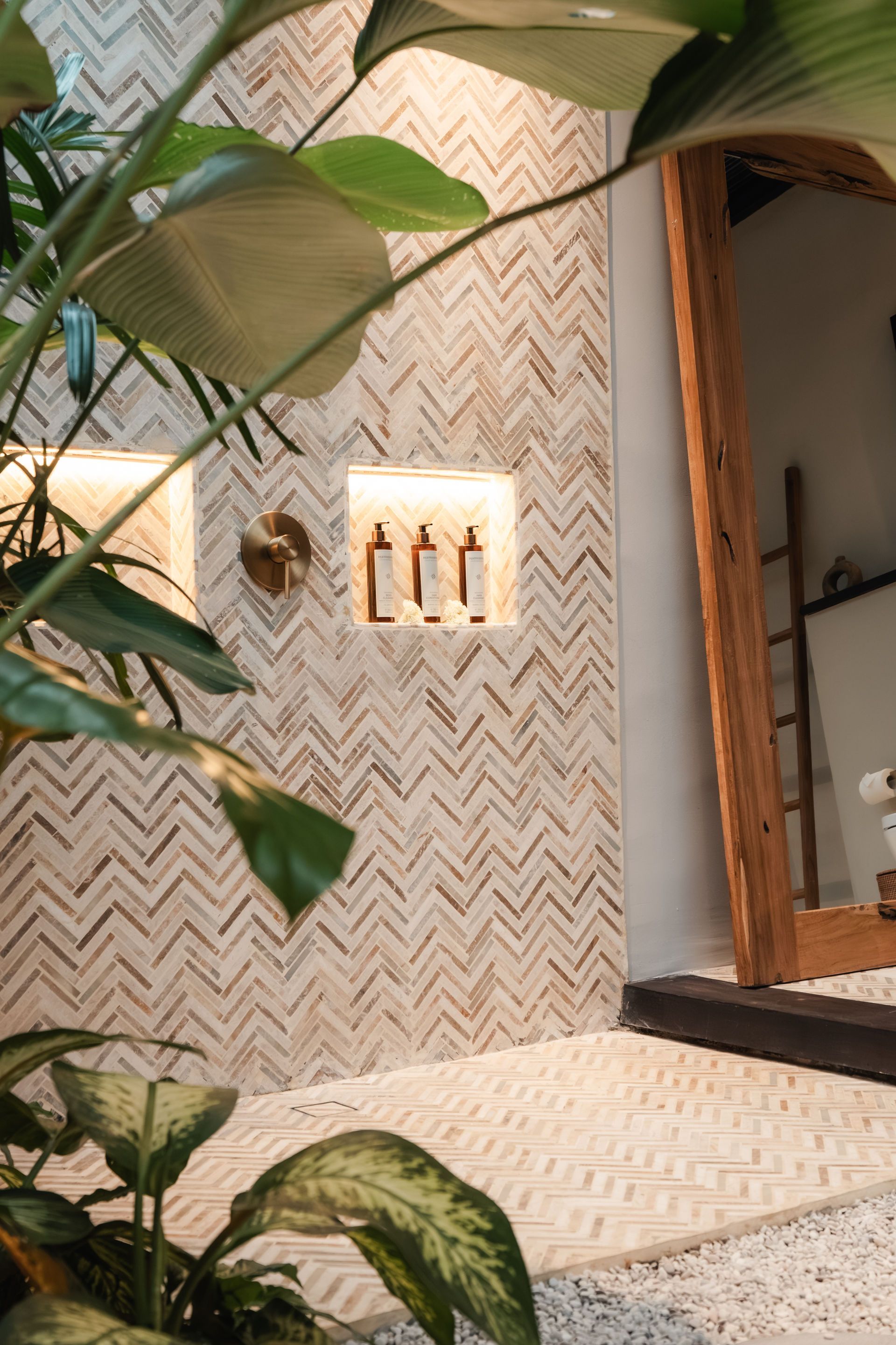 Tiled outdoor wall with a small faucet, potted plants, and an open doorway to an interior space