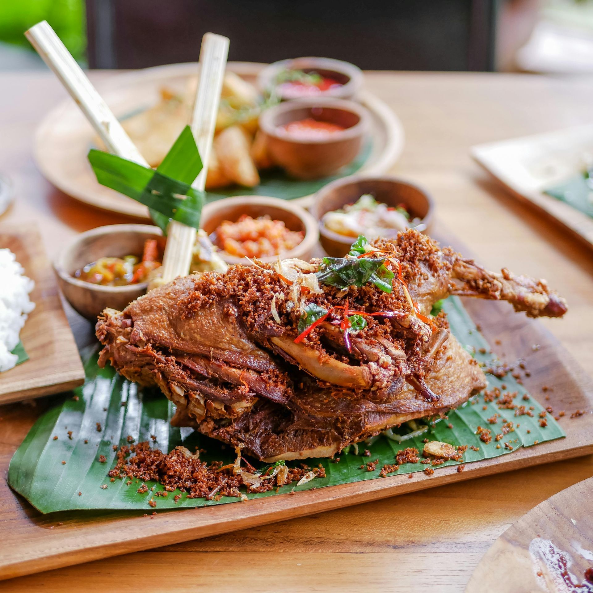 Grilled whole fish on banana leaf with sauces and rice on a wooden table