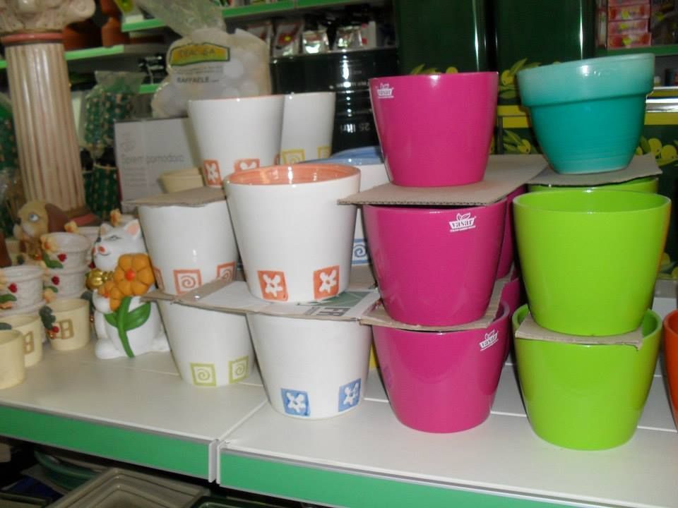 Vasi di fiori in ceramica colorati impilati su uno scaffale in un negozio.