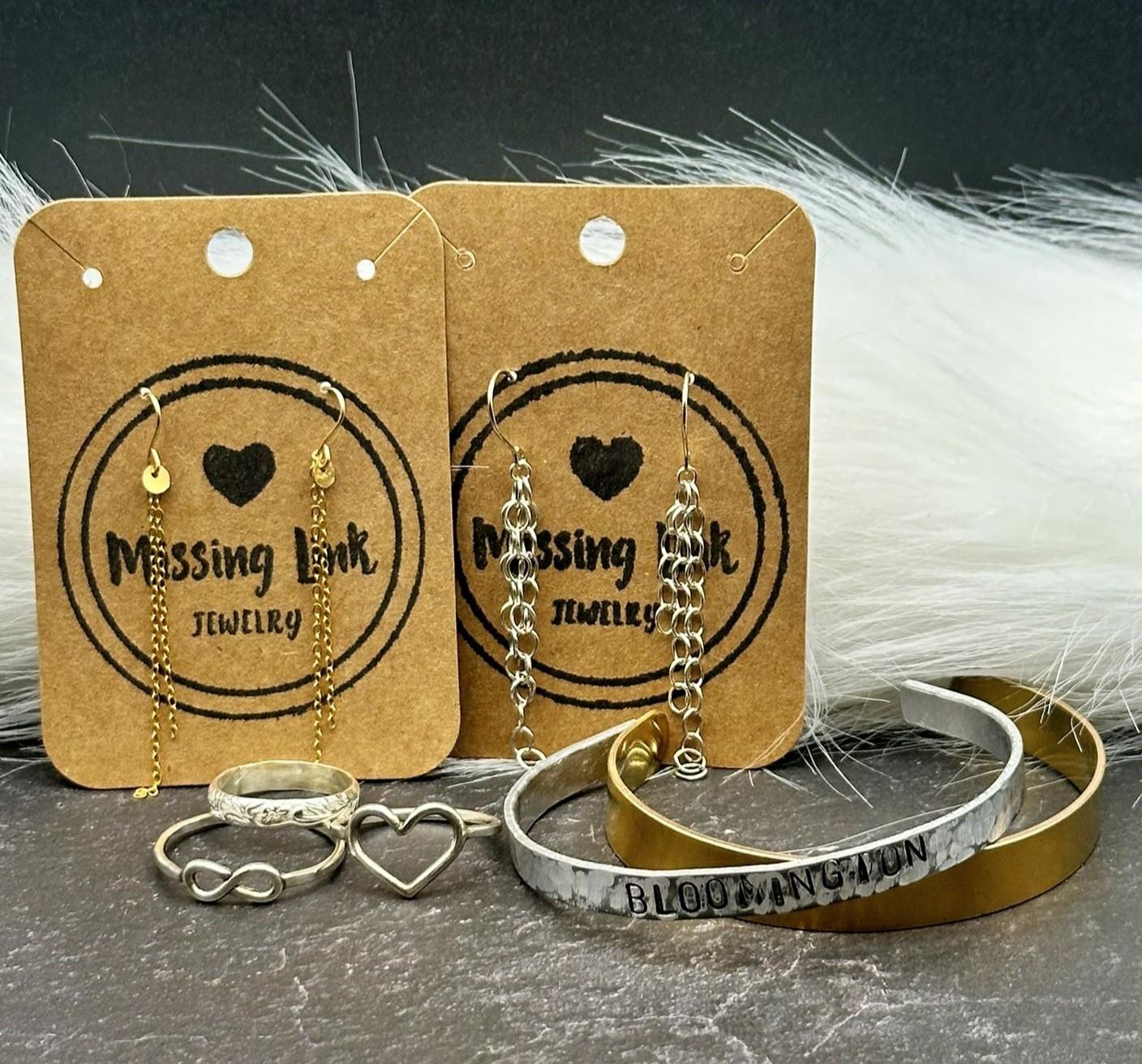 Jewelry display with earrings, rings, and bracelets on brown cards and a textured surface.