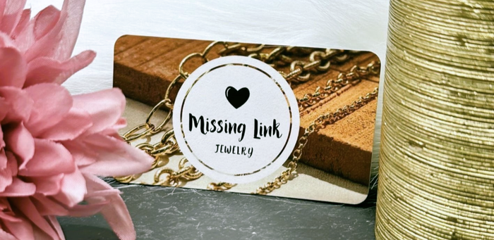 Business card for Missing link Jewelry with pink flower and gold candle in the foreground.