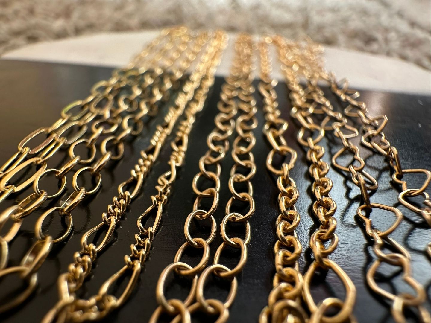 Gold chain necklaces in various styles, displayed on a dark surface.