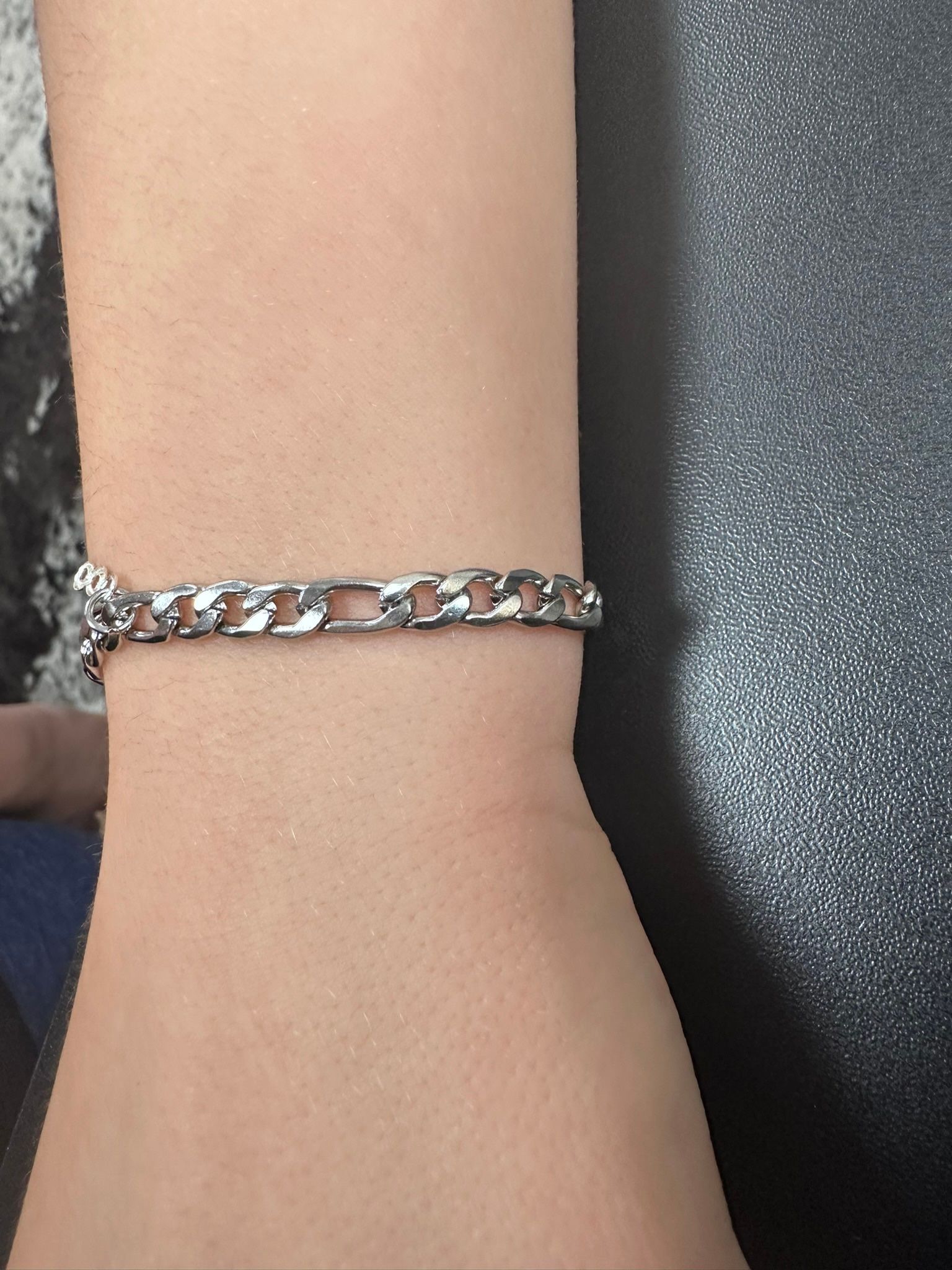 Silver chain bracelet on a wrist.