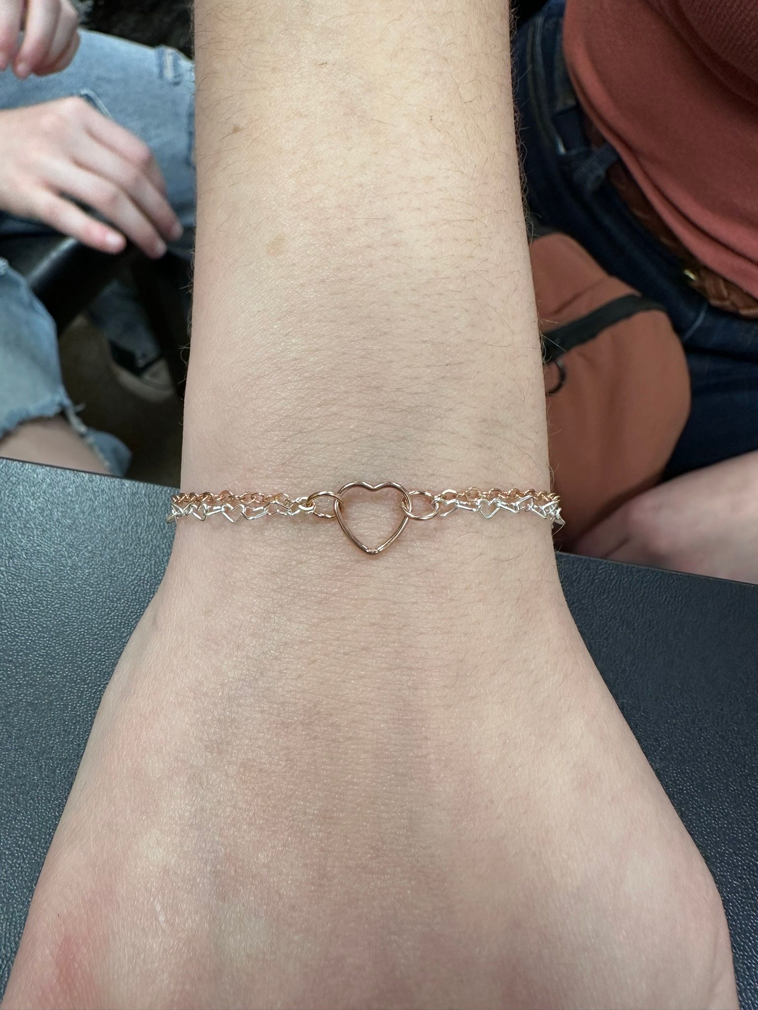 Rose gold heart bracelet on a person's wrist.