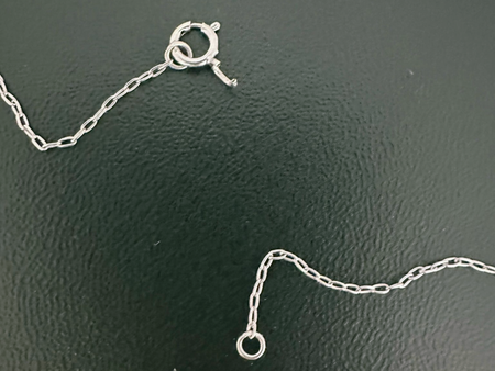 Broken silver chain on a dark surface.