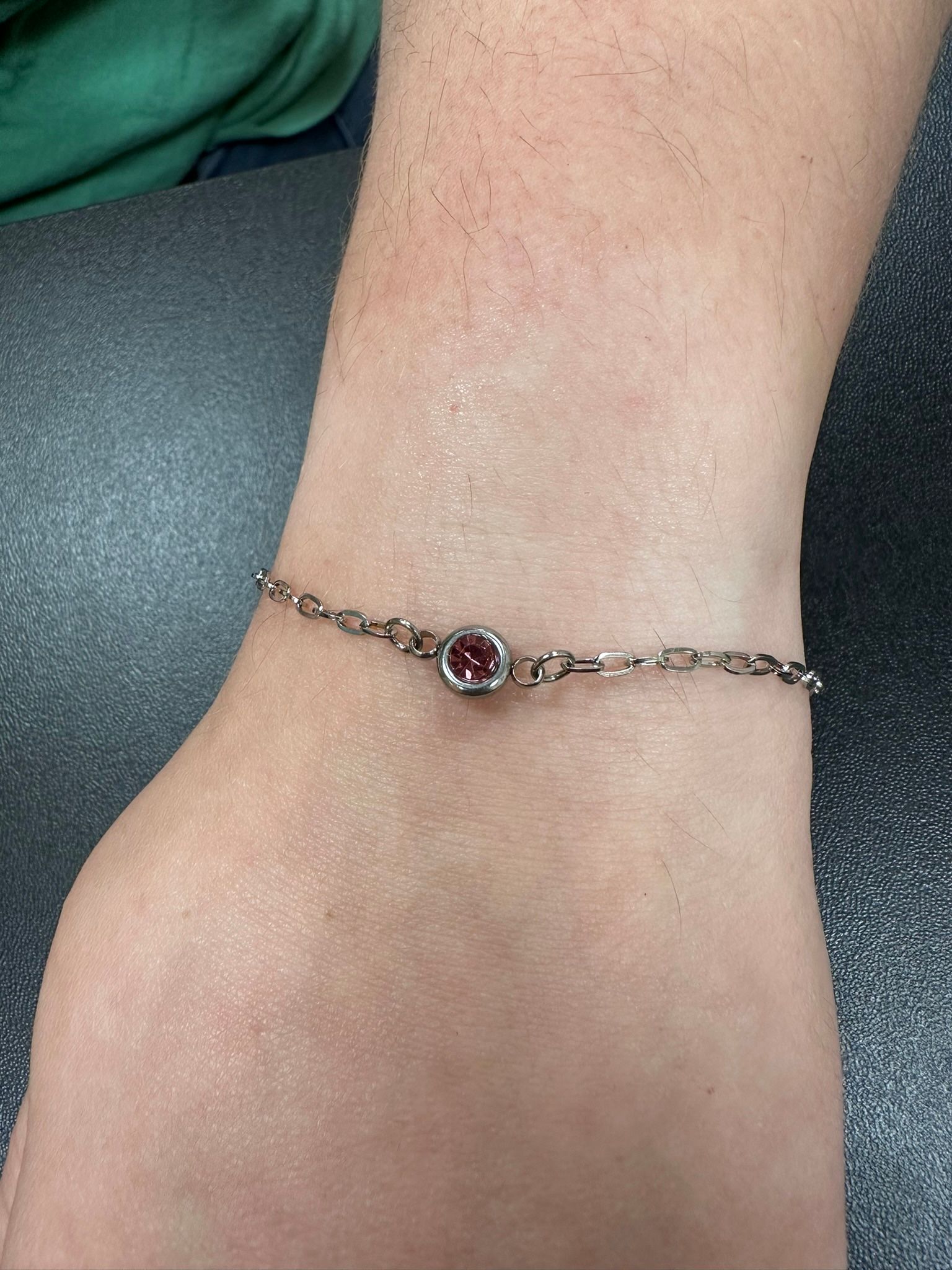 Silver bracelet with a red gemstone on a wrist.