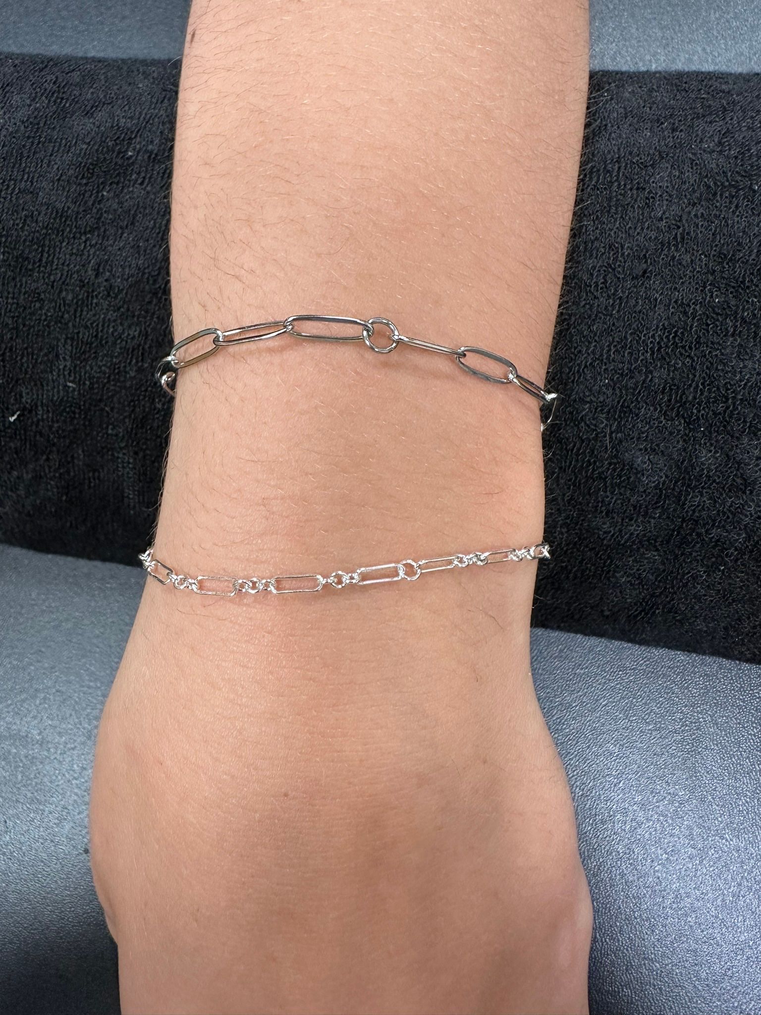 Two silver chain bracelets on a wrist.