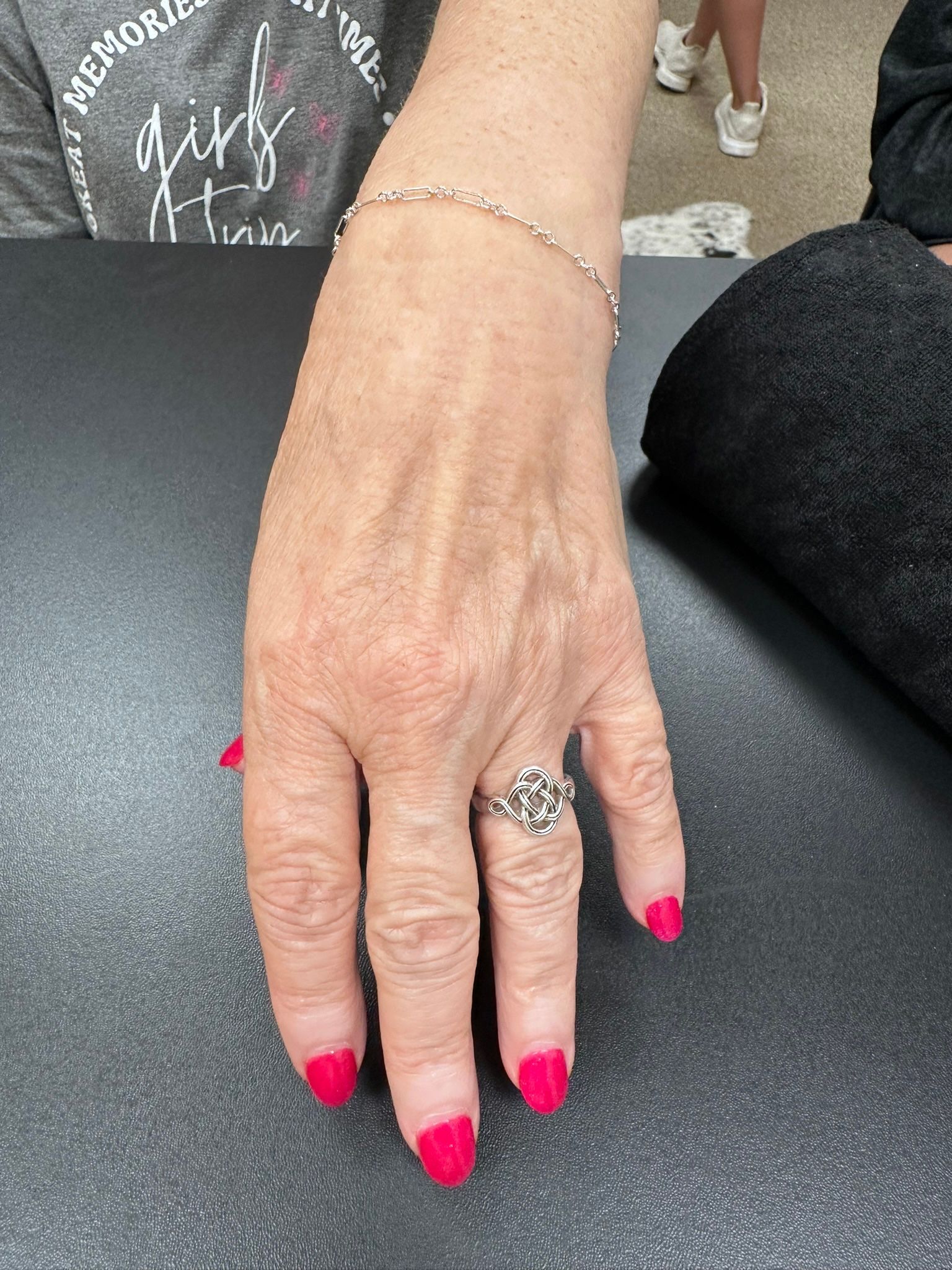 Hand with bright pink nails, silver bracelet and ring.