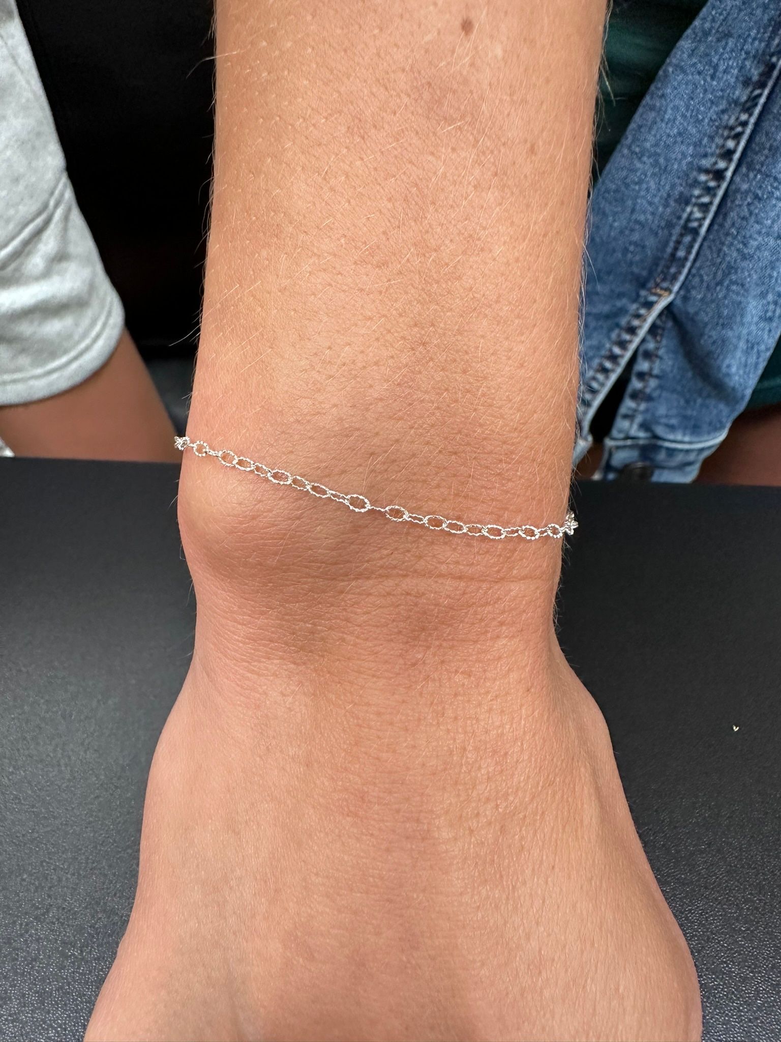 Close-up of a wrist with a silver chain bracelet.