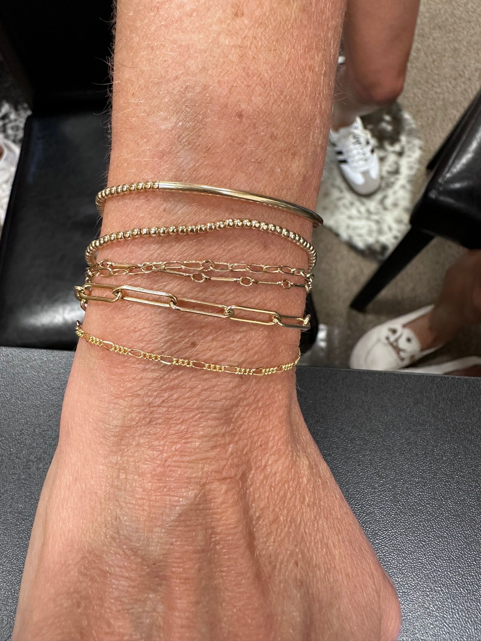 Person's arm with stack of gold bracelets.