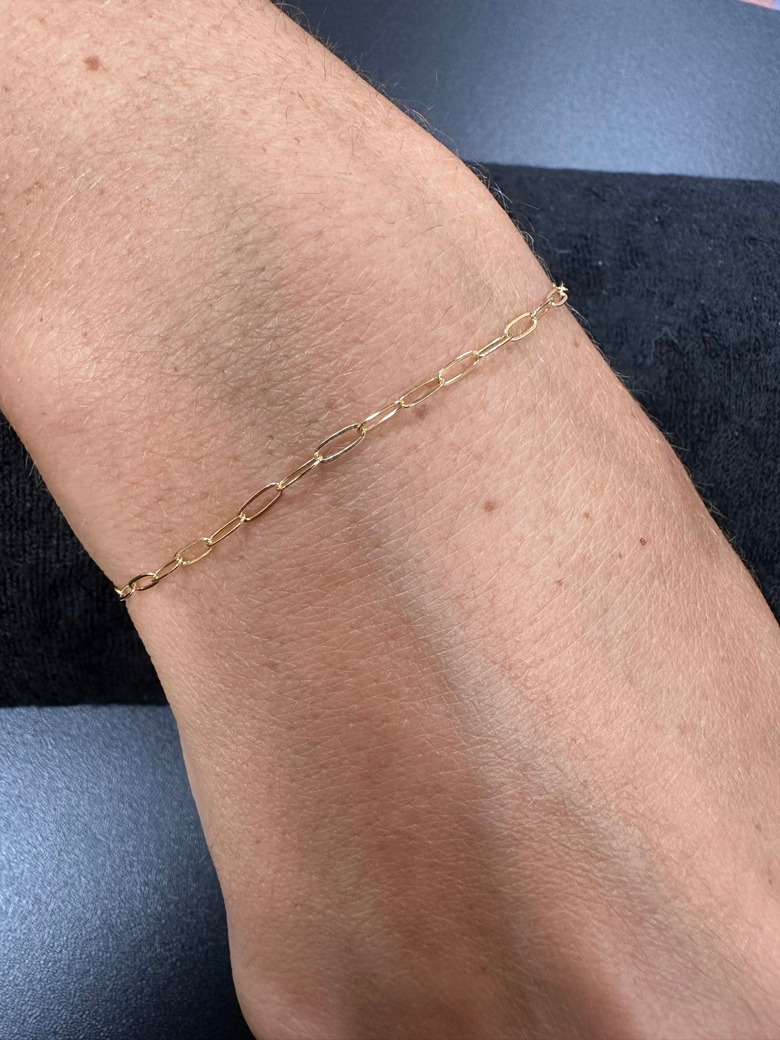 A delicate gold chain bracelet on a person's wrist.