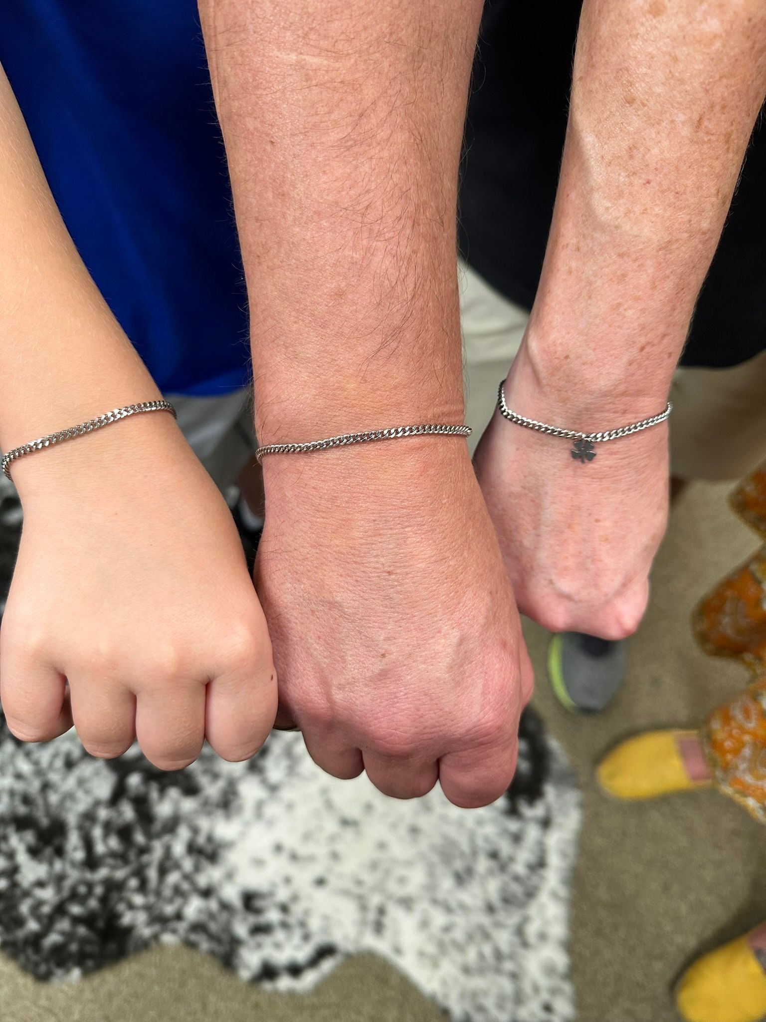 Three people wearing matching bracelets, arms extended.