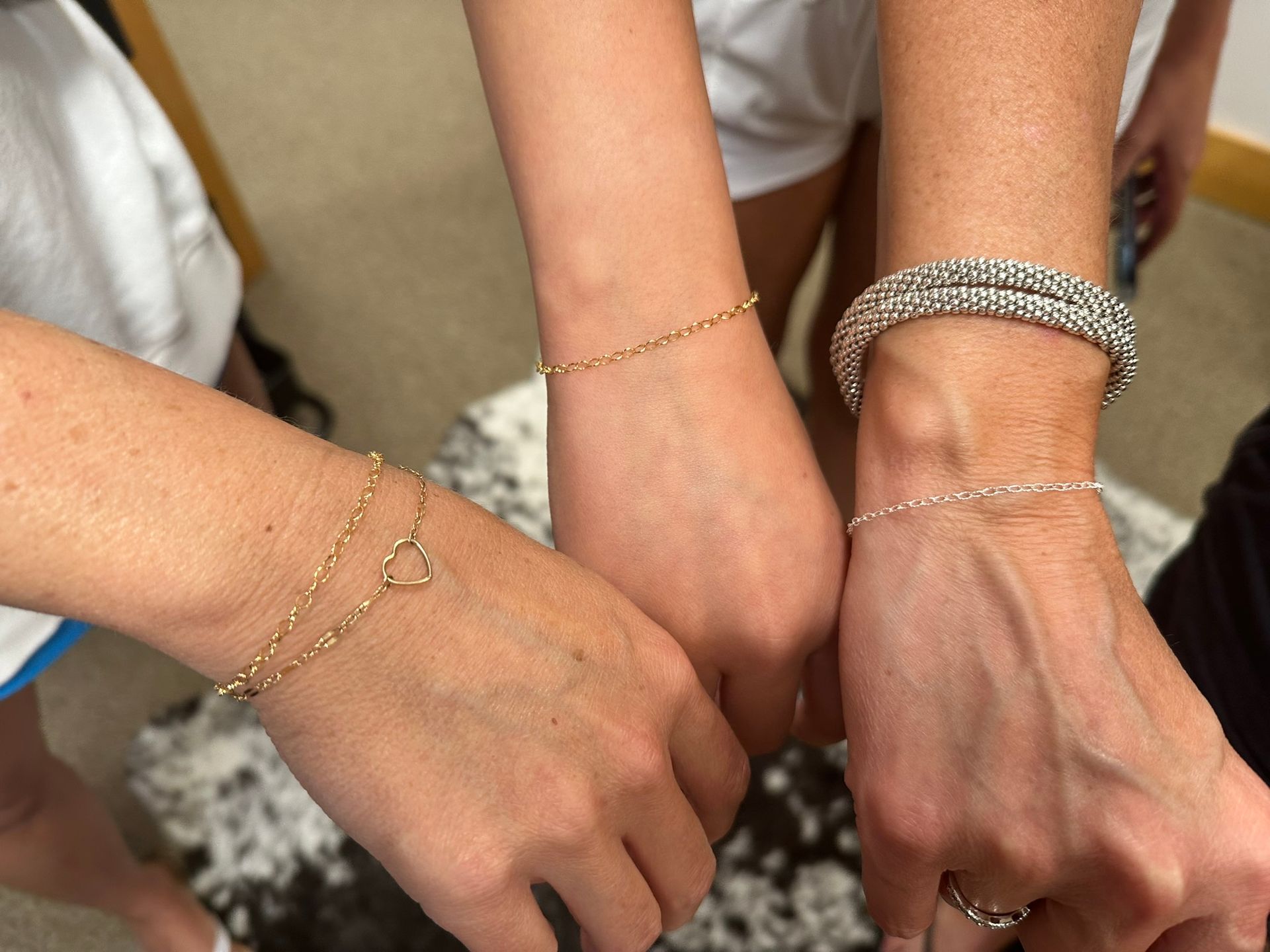 Three wrists with different bracelets.