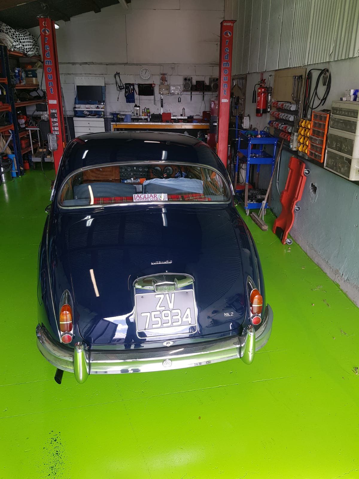 A black car is parked in a garage with a green floor.
