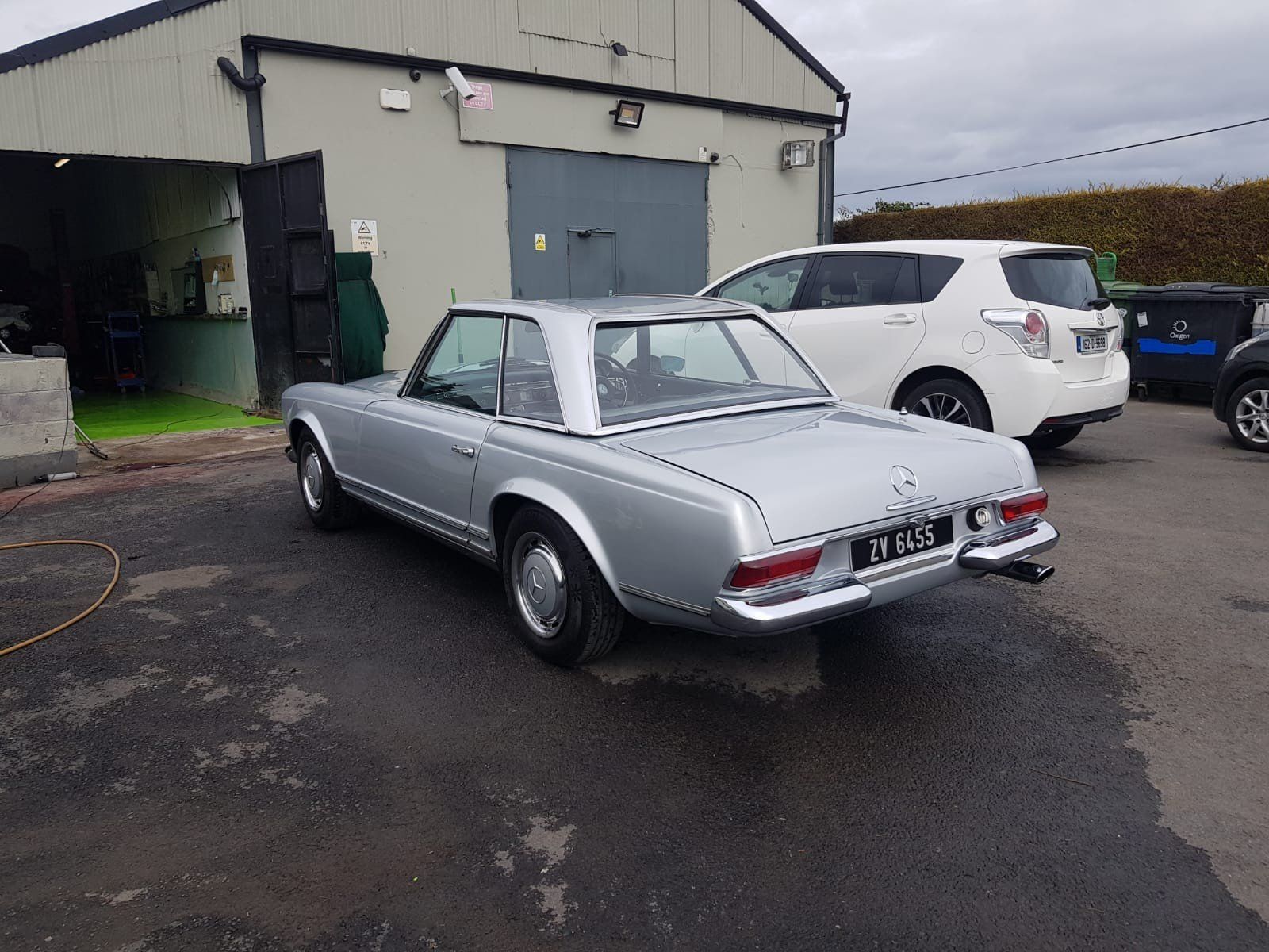 A silver car is parked in front of a building