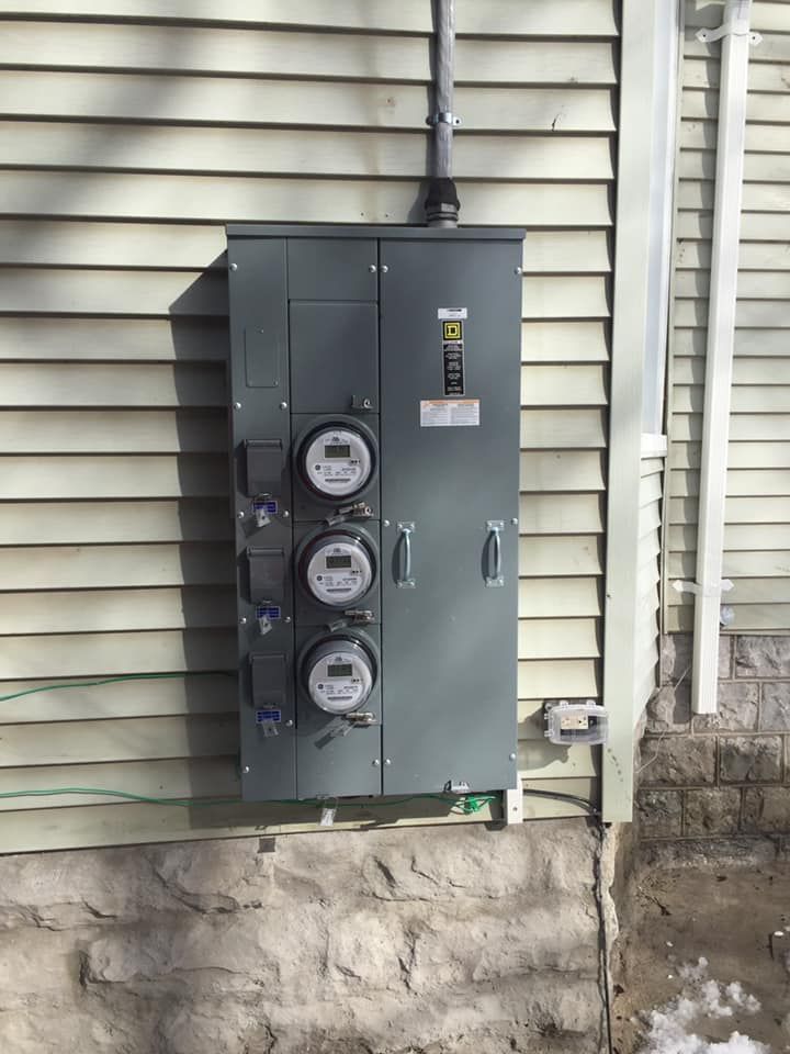 An electrical box is installed on the side of a house.
