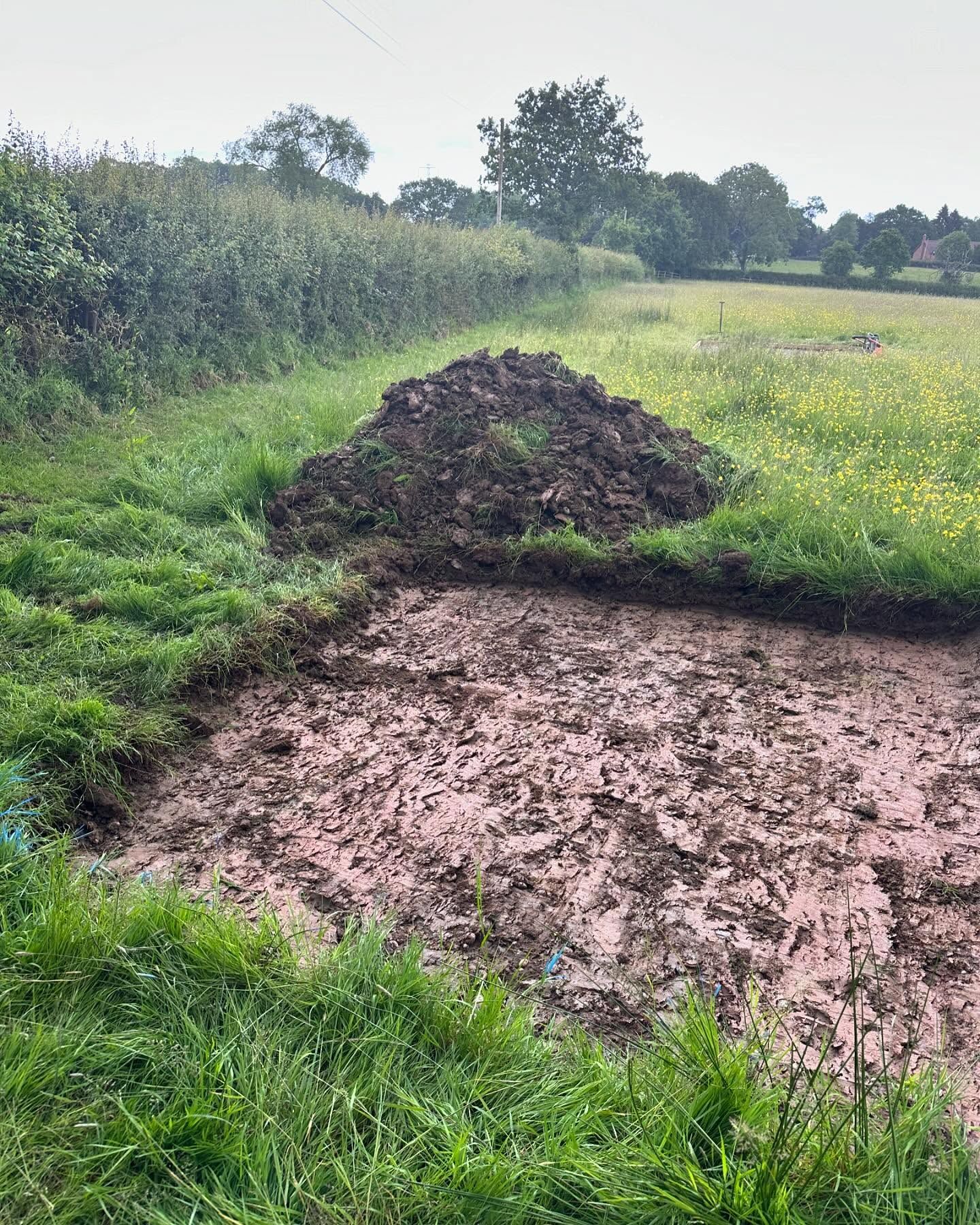 There is a large pile of dirt in the middle of a field.