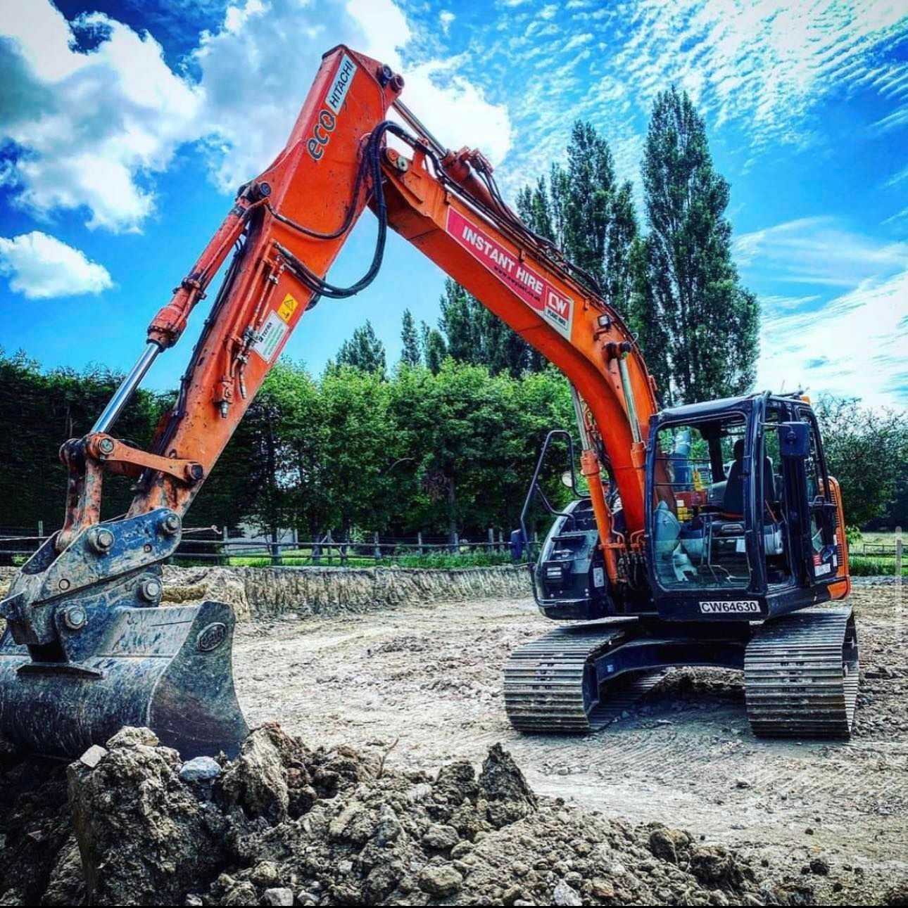 A large orange excavator is sitting in a dirt field
